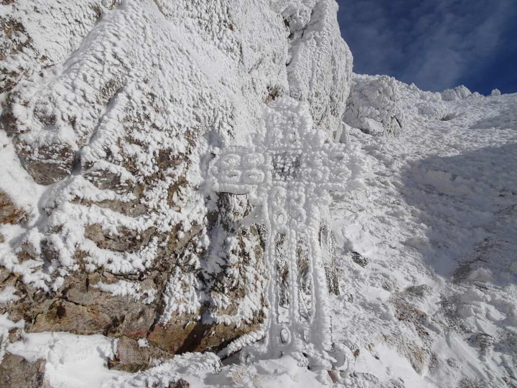 Summit cross covered in ice and snow